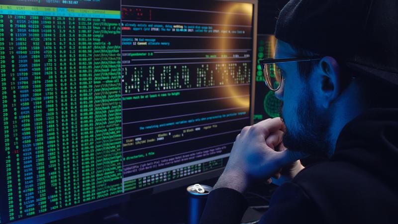 A security analyst reading log output across two monitors