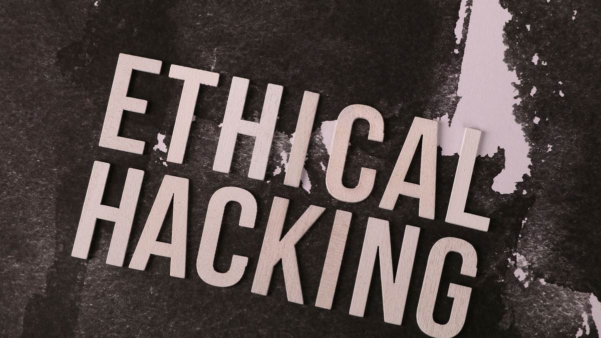 The words ethical hacking set in stencil type on a worn surface