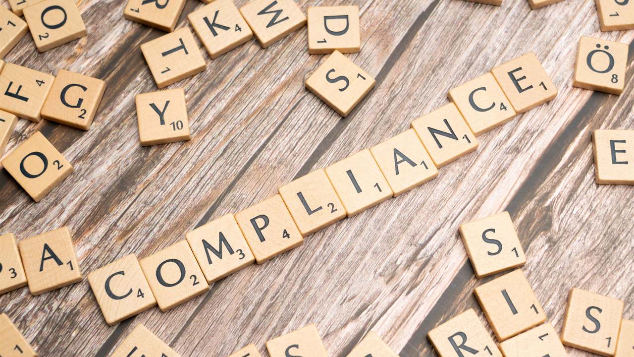 Letter tiles arranged to spell the word compliance