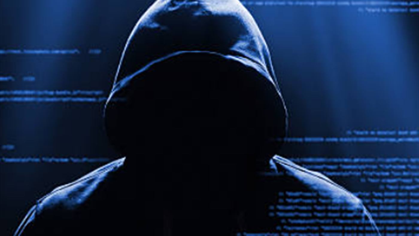 A hooded figure silhouetted against columns of code